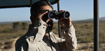 A man looking through binoculars on safari